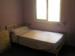 basic plain bedroom of someone renting a room to pay off debt